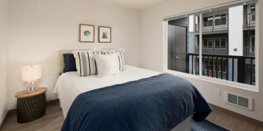 Apartment bedroom with a large window at Four Pines Apartments in Burlington, Washington
