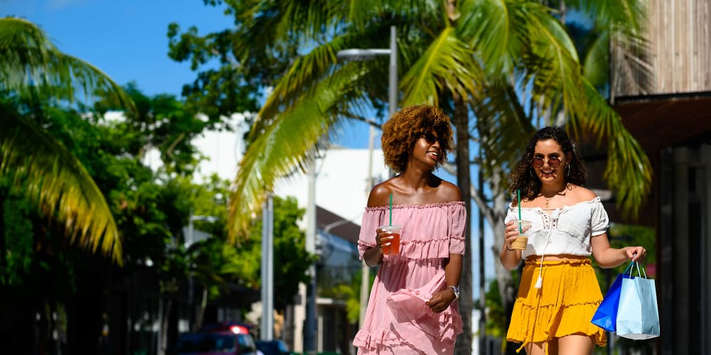 Two women walking down a street with shopping bags near The Granite at Porpoise Bay in Daytona Beach, Florida