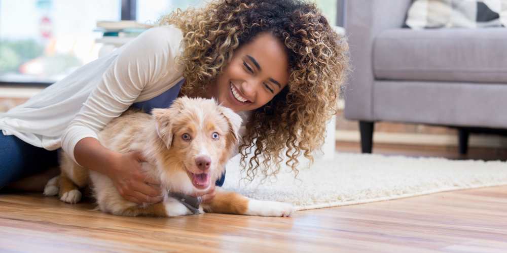 Resident and her puppy getting to know the beautiful hardwood flooring in their new apartment at Sharps & Flats Apartment Homes in Davis, California