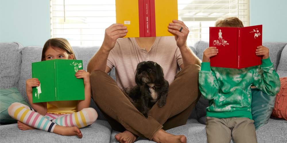 Dad and kids holding books on the couch at BB Living Wellen Park in Venice, Florida