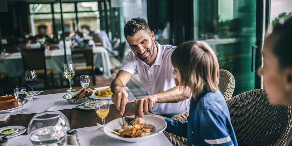 Happy family having their dinner in a restaurant at 353 Main Street Family Apartments in Redwood City, California