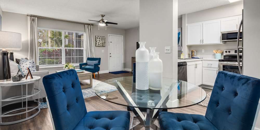 Apartment dining area with glass table and upholstered chairs at Boynton Place Apartments in Boynton Beach, Florida