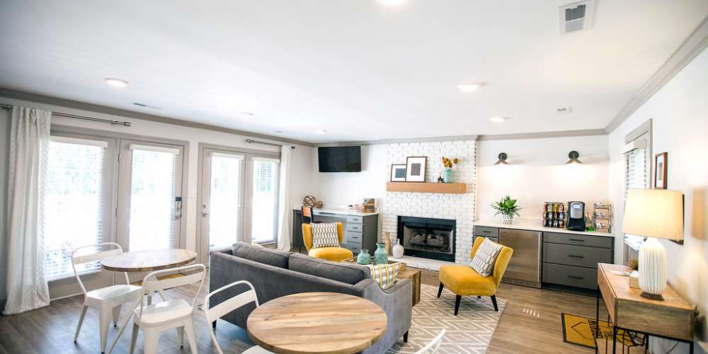 Clubhouse with sofas, tables, pantry, work desk, TV and fireplace at The Mordecai On Clover in Raleigh, North Carolina
