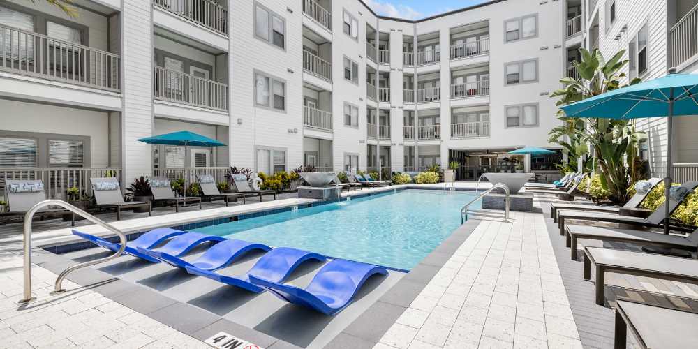 Community pool with seating and lounge chairs at SoBA Apartments in Jacksonville, Florida