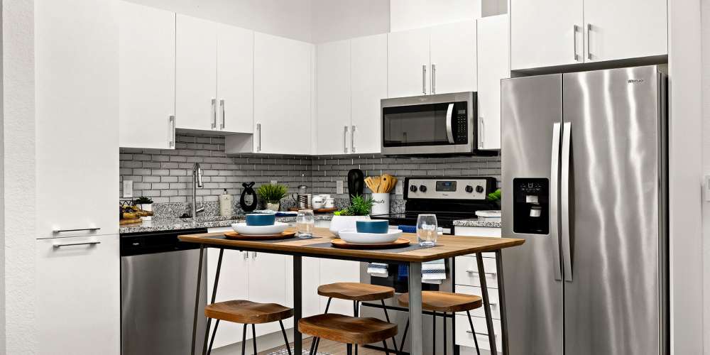 Apartment kitchen with white cabinets and stainless steel appliances at Vue on Lake Monroe in Sanford, Florida