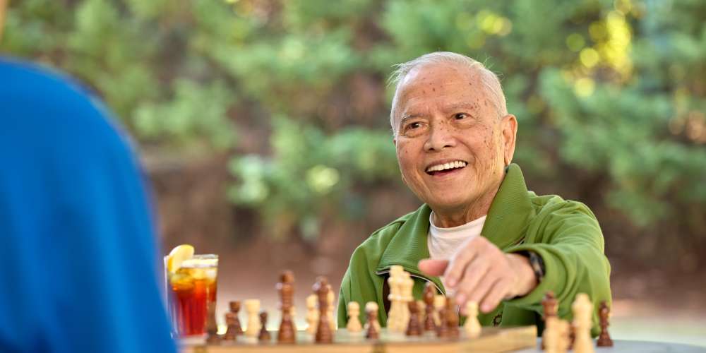 Resident playing a game of chess with his grandson at a QSL Management community 