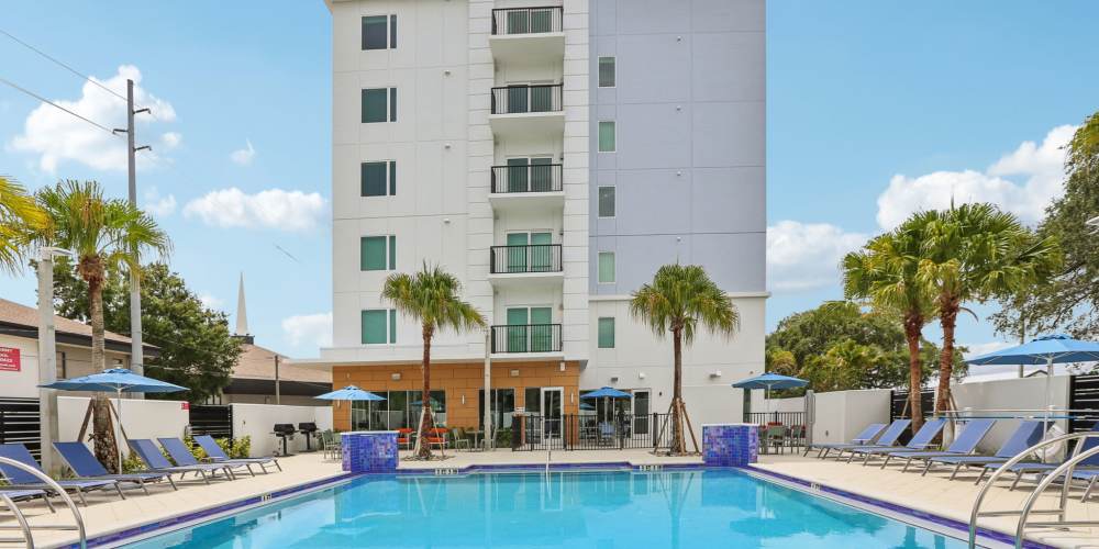 Community pool with lounge chair  at The Breeze in Winter Haven, Florida