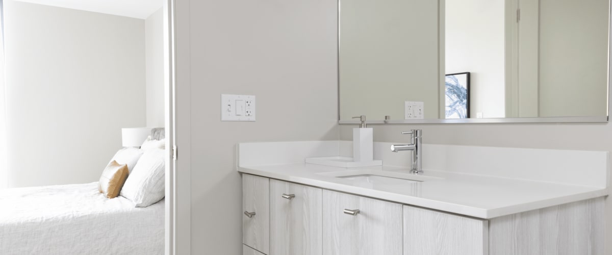 Interior of bathroom sink, cabinets, and mirror looking into bedroom at Solaire 8200 Dixon in Silver Spring, Maryland