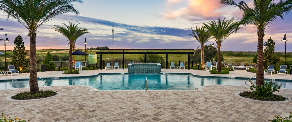 The sparkling community swimming pool surrounded by seating at Integra Heights in Clermont, Florida