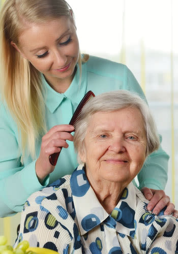 A caregiver brushes a resident's hair at Wyndham Court of Plano in Plano, Texas