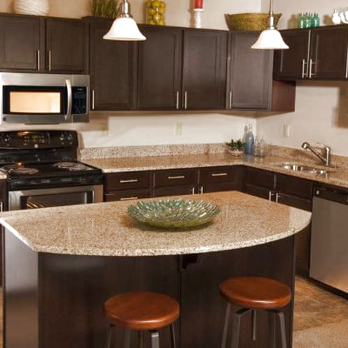 Open concept model kitchen with granite countertops and stainless steel appliances at Rochester Village Apartments at Park Place in Cranberry Township, Pennsylvania