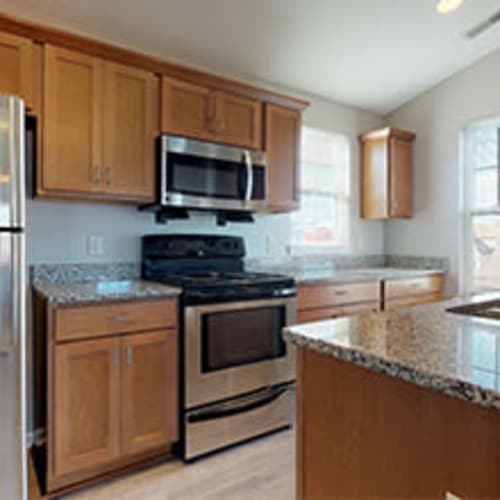 Modern kitchen with stainless steel appliances and an in-home washer and dryer at Webster Green in Webster, New York