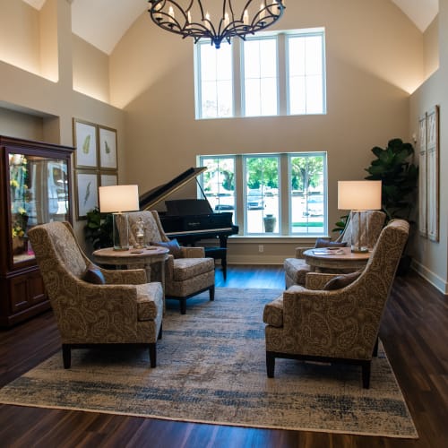 Brightly lit entrance lobby with comfortable armchairs and piano at Westminster Memory Care in Lexington, South Carolina