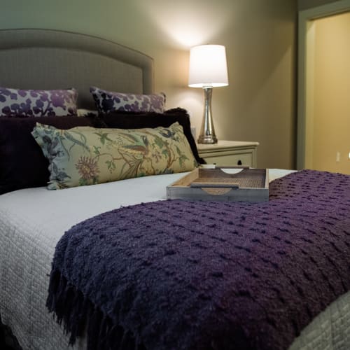 Comfortable resident bedroom with full-size bed and side table at Westminster Memory Care in Lexington, South Carolina