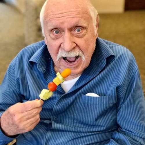 Resident eating a fruit kabob at Oxford Glen Memory Care at Carrollton in Carrollton, Texas