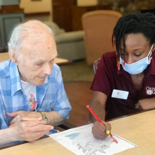 Resident coloring with caretaker at Oxford Glen Memory Care at Carrollton in Carrollton, Texas