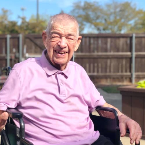 Resident smiling outside in a wheelchair at a Oxford Senior Living community