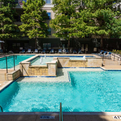 Water feature in center of sparkling pool with lounge chairs in back of Marquis at Texas Street in Dallas, Texas