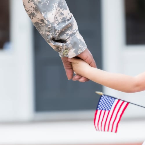 a resident holding their child's hand, who is holding an American flag at Santa Rosa in Point Mugu, California