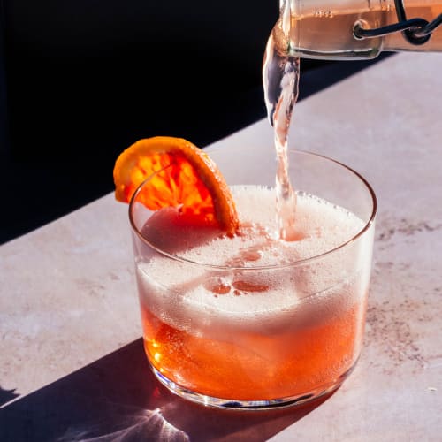 Pouring a tasty looking cocktail that has a slice of orange in it at Big Sky Flats in Washington, District of Columbia