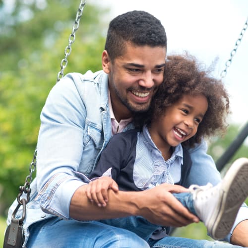 a father and daughter playing on the swings near  River Place in Lakeside, California