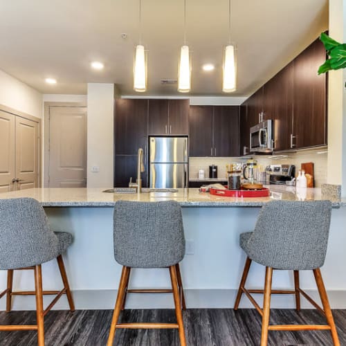 Bar seating in a model home's modern kitchen with granite countertops at The Nash in Dallas, Texas