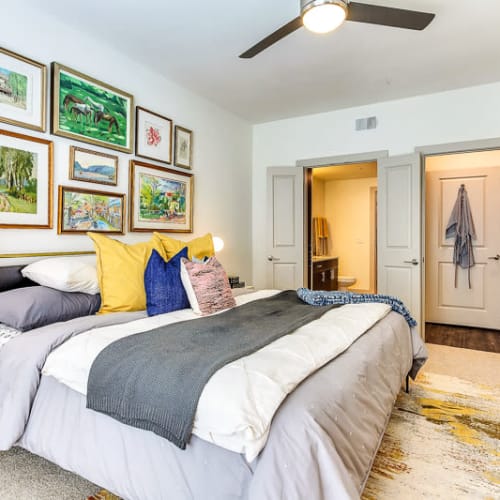Ceiling fan and a walk-in closet in the well-furnished primary bedroom of a model home at The Nash in Dallas, Texas