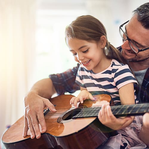 a father teaching his daughter to play guitar at Forster Hills in Oceanside, California
