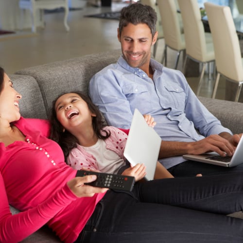 a resident family laughing on the couch at Norwich Manor in Norfolk, Virginia