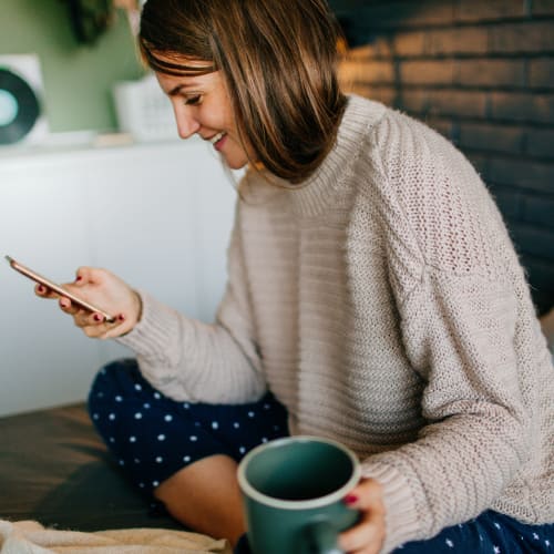 a resident drinking coffee looking at her phone at Sea Breeze Village in Seal Beach, California