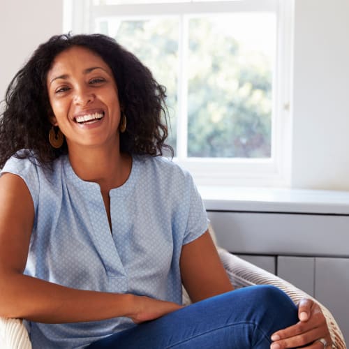 a resident smiling on the couch at Sea Breeze Village in Seal Beach, California