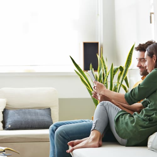 residents sitting on the couch reading a a tablet at Mira Mesa Ridge in San Diego, California