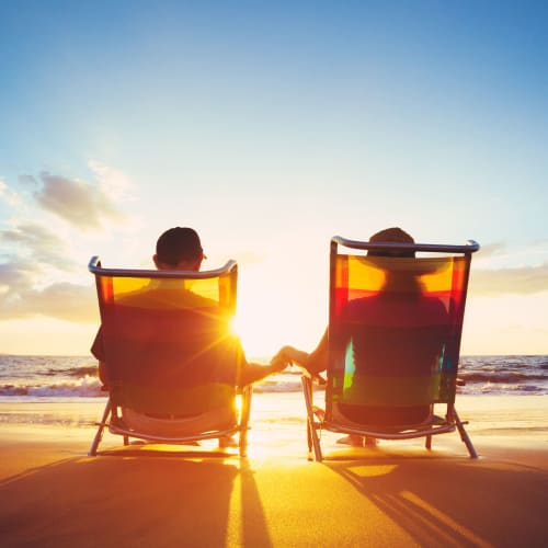 Couple relaxing on beach chairs and enjoying the gorgeous sunset near The Crossing at Palm Aire Apartment Homes in Sarasota, Florida 