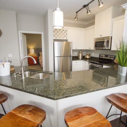 Model kitchen with granite counters and bar stools at The Residences at New Longview in Lees Summit, Missouri
