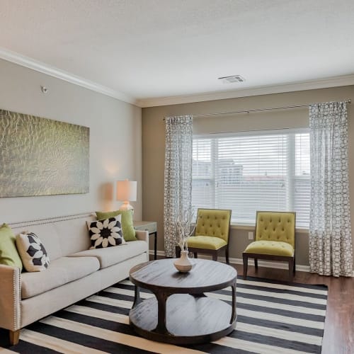 Living room with large windows and wood-style flooring at The Residences at New Longview in Lees Summit, Missouri