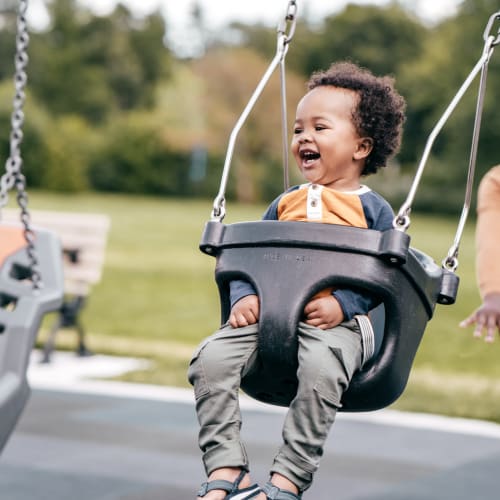 Resident pushing her child on a swing set at The Addison, North Wales, Pennsylvania