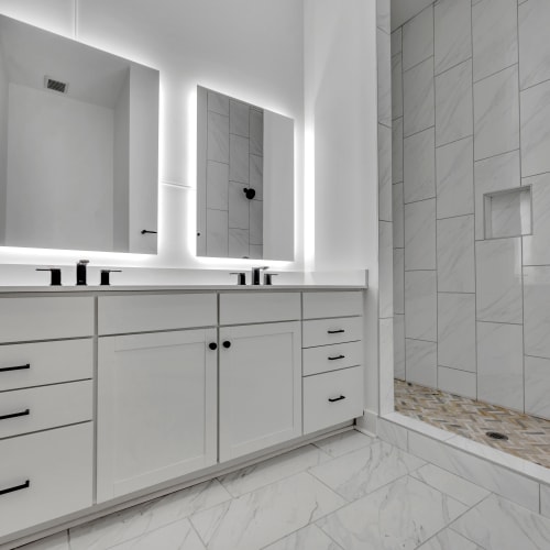A modern bathroom with double vanity and walk-in shower at Theatre Lofts in Birmingham, Alabama