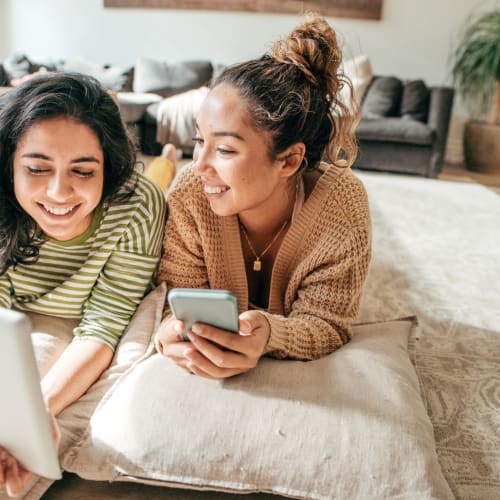 Residents laying on the floor of their new living room looking at their tablet and phone at Iron Ridge in Elkton, Maryland