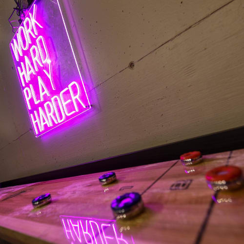 Shuffleboard table and neon sign in the resident lounge at Landmark Glenmont Station in Silver Spring, Maryland