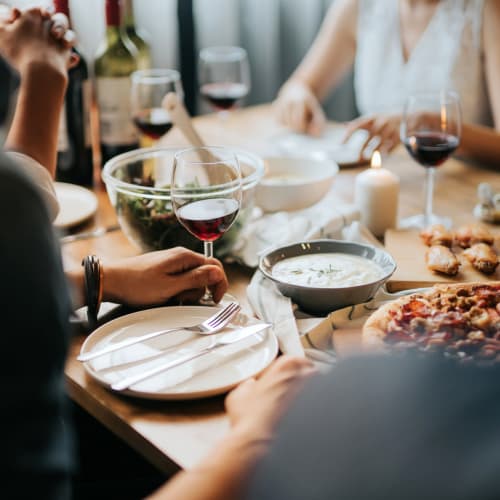 Friends sharing a bottle of wine and pizza at a favorite restaurant near Landmark Glenmont Station in Silver Spring, Maryland