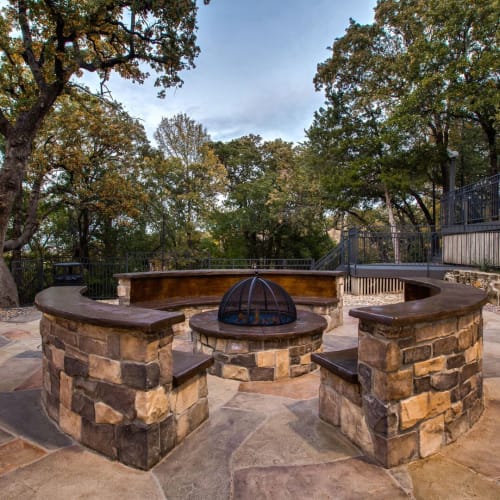 Outdoor seating around a fireplace at Verandahs at Cliffside Apartments in Arlington, Texas