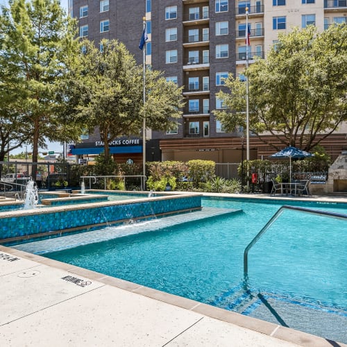 Water feature in center of sparkling pool with lounge chairs in back of Marquis at Texas Street in Dallas, Texas