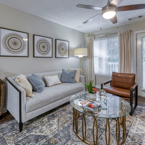 A furnished living room with a ceiling fan in an apartment at The Glen at Lanier Crossing in Stockbridge, Georgia
