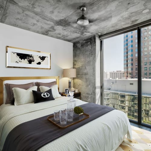 Modern apartment bedroom with grey textured walls and large windows at Josephine DTLA in Los Angeles, California