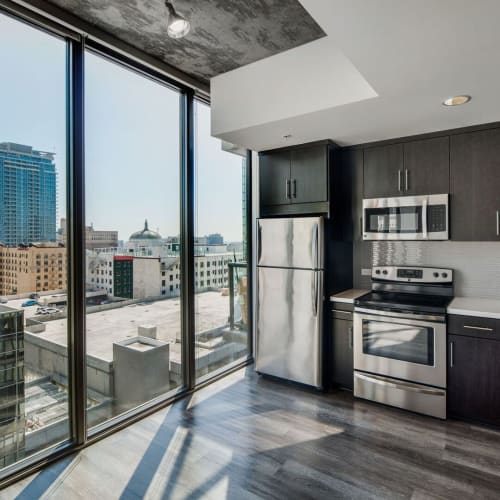 Apartment kitchen with large windows and stainless-steel appliances at Josephine DTLA in Los Angeles, California