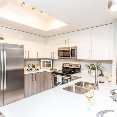 Fully equipped kitchen with granite countertops stainless steel appliances like a refrigerator, stove, and drawer microwave at Club Prado in West Miami, Florida
