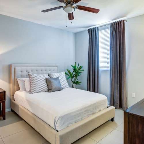 Cozy bedroom with a bed, fan and large window at Club Prado in West Miami, Florida