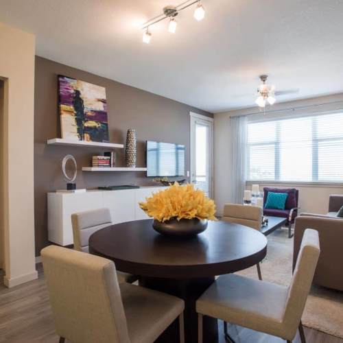 Well-lit living room with a couch, large windows, wall-mounted TV and a dining table at Elevation @ County Line Station in Englewood, Colorado