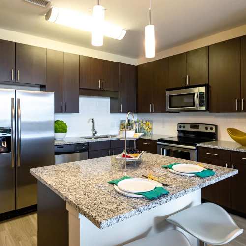 Modern kitchen with wooden cabinets and granite breakfast counter at Elevation @ County Line Station in Englewood, Colorado