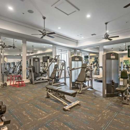 Fully-equipped gym with treadmills, flat-screen television, and ceiling fans at {location_name}} in Plantation, Florida